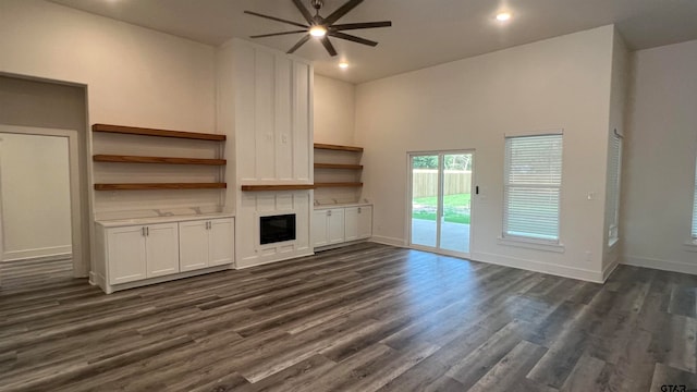 unfurnished living room featuring a high ceiling, ceiling fan, and dark hardwood / wood-style flooring