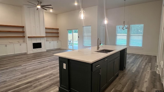 kitchen featuring a high ceiling, decorative light fixtures, sink, and light stone counters