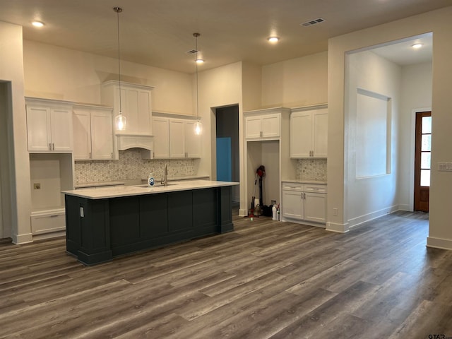 kitchen with dark wood-type flooring, white cabinetry, and a kitchen island with sink