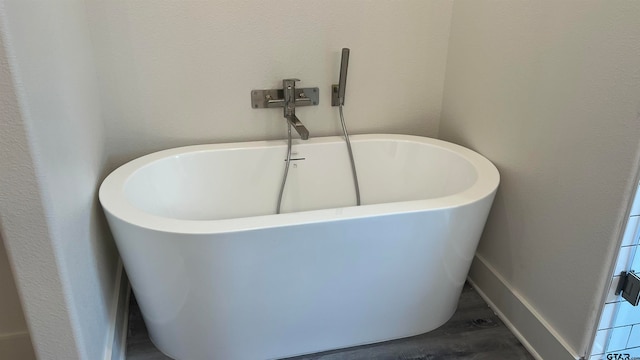 bathroom with hardwood / wood-style flooring and a tub to relax in