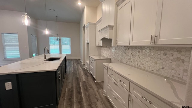 kitchen featuring white cabinetry, pendant lighting, sink, and a large island with sink