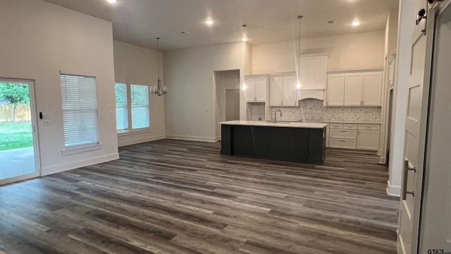 kitchen with dark wood-type flooring, white cabinetry, plenty of natural light, and a kitchen island with sink