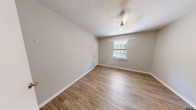 empty room with light hardwood / wood-style floors and a textured ceiling