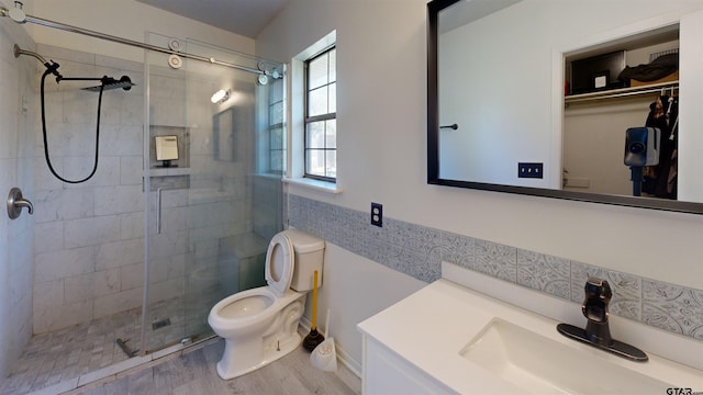 bathroom featuring hardwood / wood-style flooring, a shower with shower door, vanity, and toilet