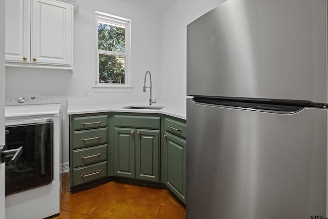 laundry area with dark tile patterned floors, cabinet space, washer / clothes dryer, and a sink