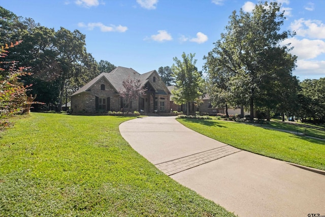 view of front of property with stone siding, concrete driveway, and a front lawn