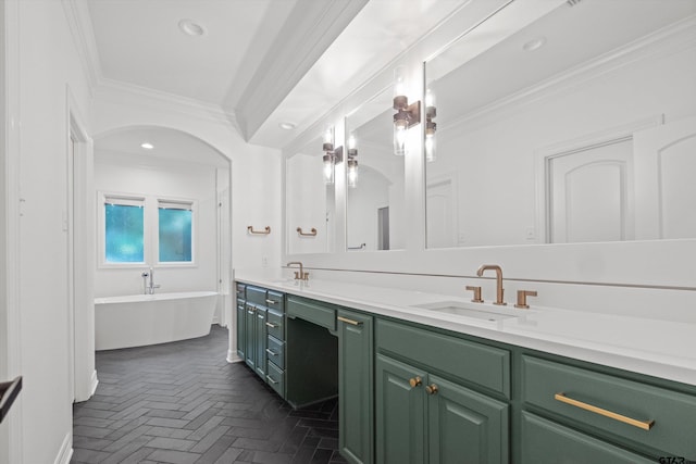 full bathroom featuring a sink, a freestanding bath, ornamental molding, and double vanity