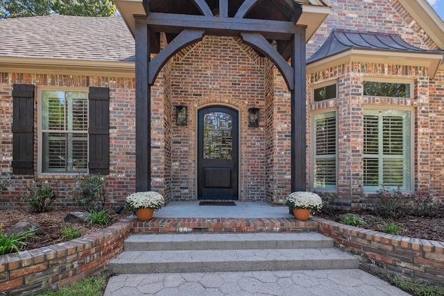 property entrance with brick siding, covered porch, and a shingled roof