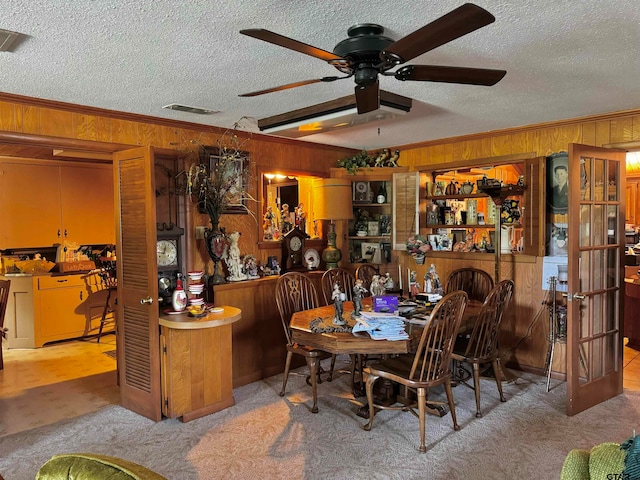 dining space featuring wood walls, a textured ceiling, ceiling fan, and crown molding