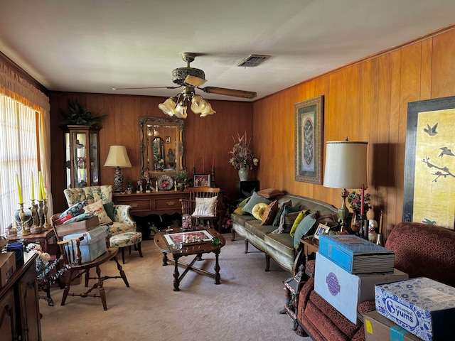 carpeted living room featuring wood walls and ceiling fan