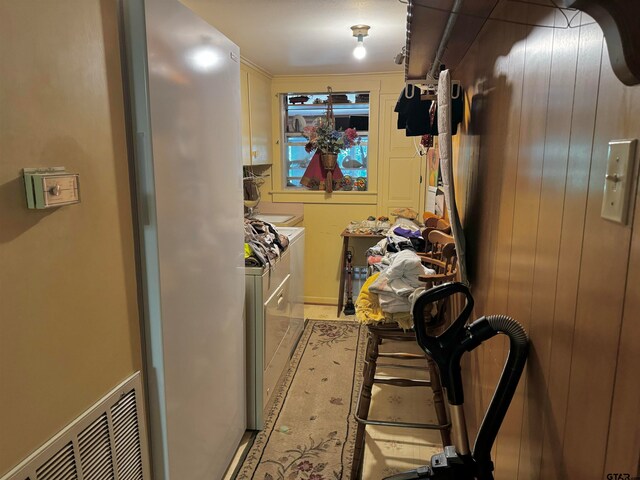 laundry area featuring wood walls, cabinets, and independent washer and dryer