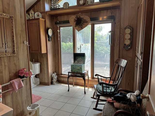 sitting room featuring wooden walls and light tile patterned floors