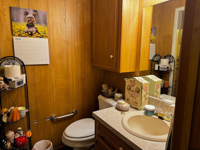 bathroom with wood walls, vanity, and toilet