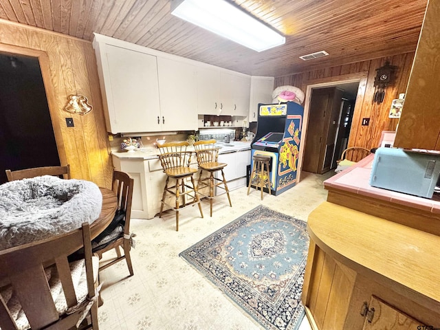 1115 Sunset Ave, Jacksonville, TX 75766 - kitchen featuring wood ceiling, wooden walls, white cabinetry, light countertops, and light flooring