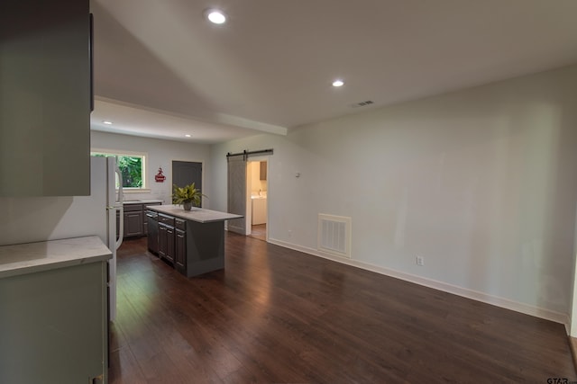 kitchen featuring gray cabinets, a barn door, dark hardwood / wood-style floors, and a kitchen island