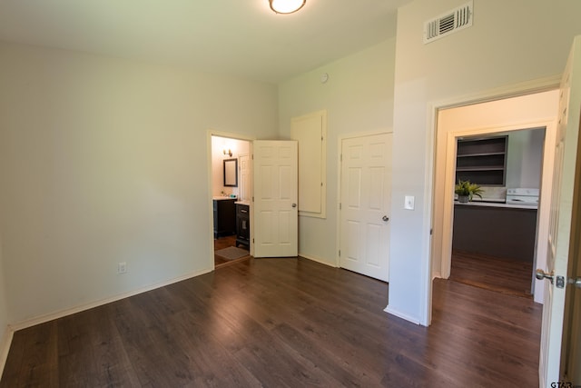 unfurnished bedroom featuring ensuite bath, dark hardwood / wood-style floors, and a closet