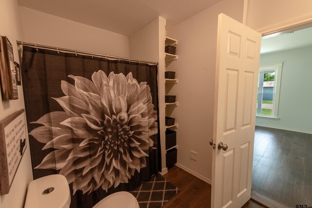 bathroom featuring toilet, hardwood / wood-style flooring, and curtained shower