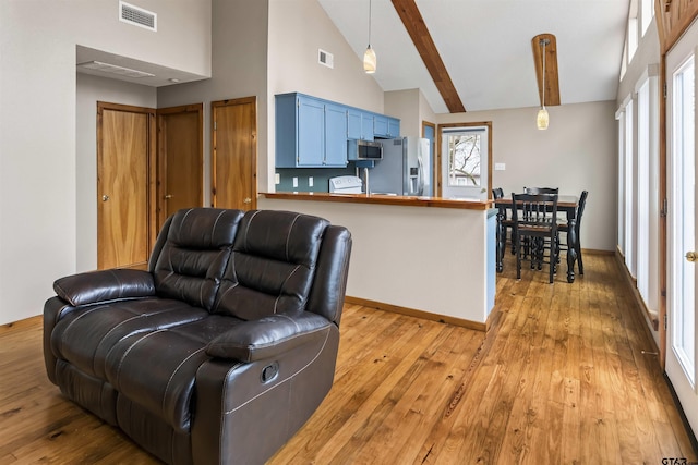 living room featuring beamed ceiling, light wood-type flooring, and high vaulted ceiling