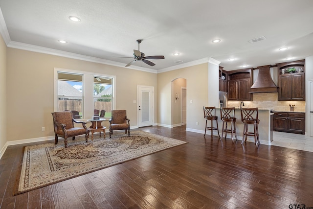 sitting room featuring crown molding, arched walkways, baseboards, and visible vents