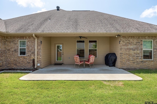 back of house with a shingled roof, a yard, brick siding, and ceiling fan