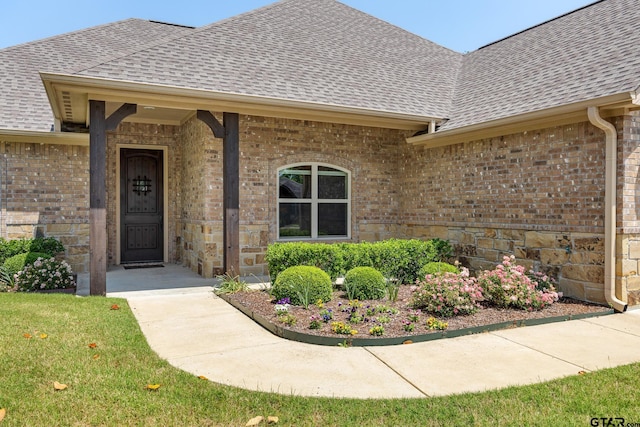 doorway to property featuring roof with shingles and brick siding