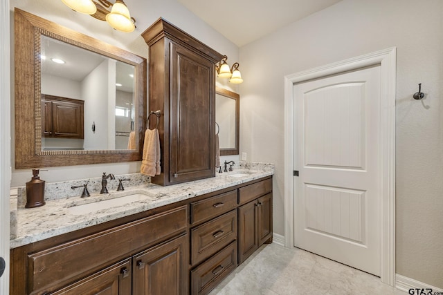 bathroom with a sink, baseboards, tile patterned floors, and double vanity