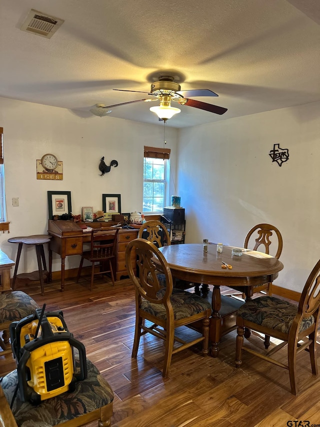 dining area with dark wood-type flooring, a textured ceiling, and ceiling fan