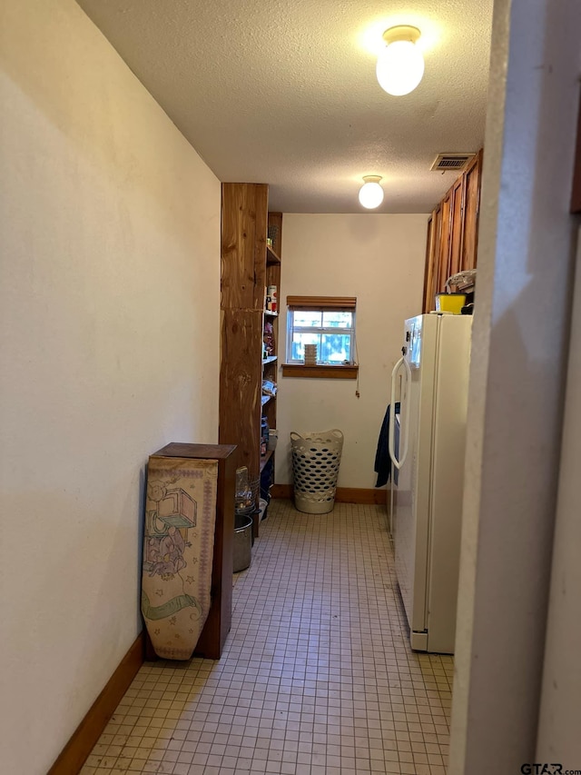 laundry room featuring cabinets, a textured ceiling, and light tile patterned floors