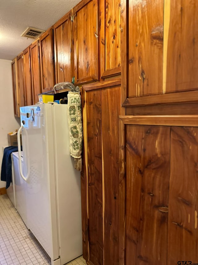 laundry room with a textured ceiling and light tile patterned floors