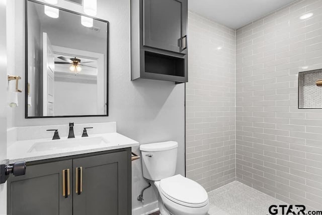 bathroom featuring vanity, ceiling fan, toilet, and tiled shower