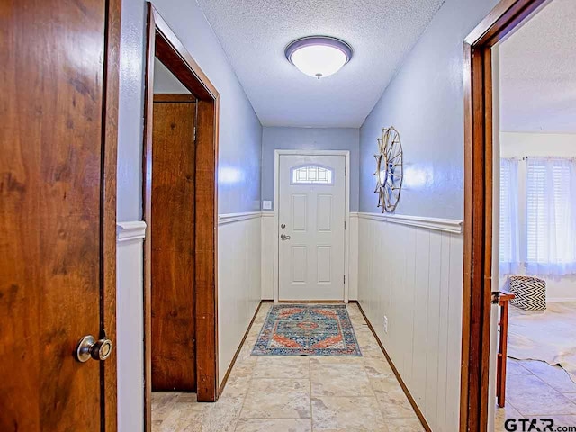 doorway to outside featuring wood walls, a textured ceiling, and plenty of natural light