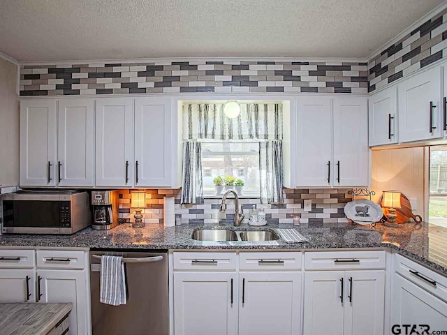 kitchen with a textured ceiling, stainless steel appliances, white cabinetry, and sink