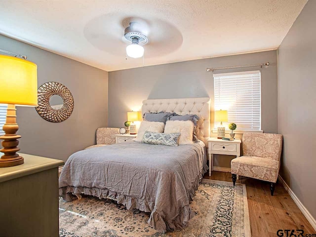 bedroom with ceiling fan, a textured ceiling, and hardwood / wood-style flooring