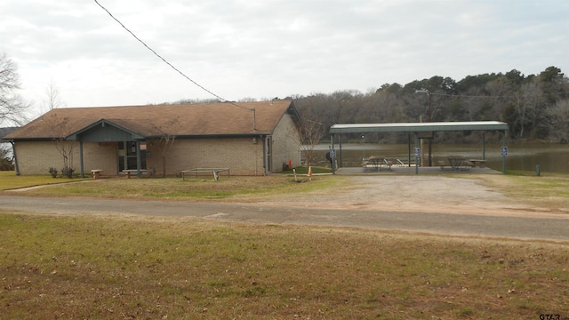 view of front facade featuring brick siding, a front yard, driveway, and a carport