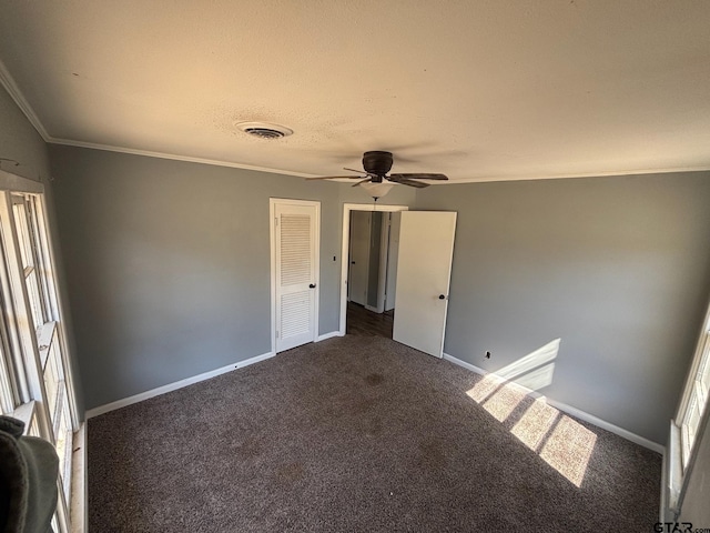 unfurnished bedroom with dark colored carpet, ornamental molding, visible vents, and baseboards