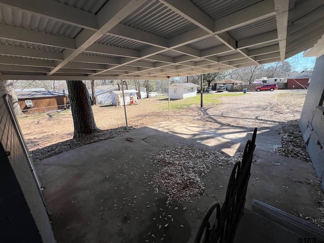 view of patio / terrace with a carport, an outbuilding, fence, and a storage unit