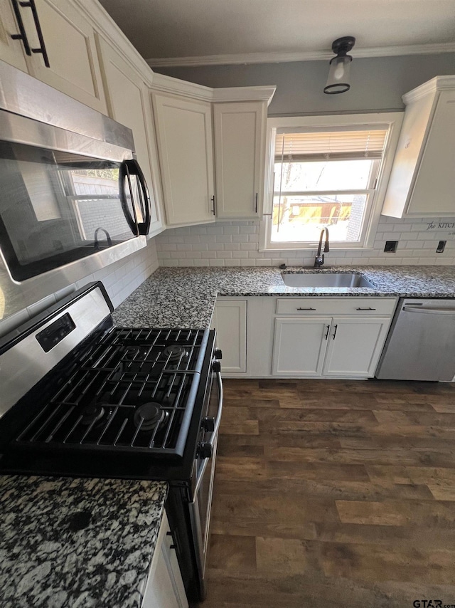 kitchen featuring appliances with stainless steel finishes, crown molding, a sink, and light stone counters