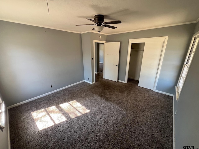 unfurnished bedroom featuring crown molding, a closet, dark carpet, a ceiling fan, and baseboards