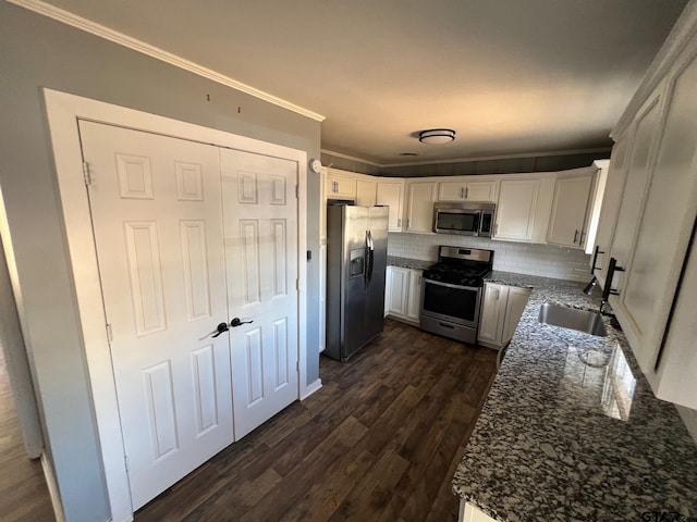 kitchen with appliances with stainless steel finishes, crown molding, a sink, and dark wood-style floors