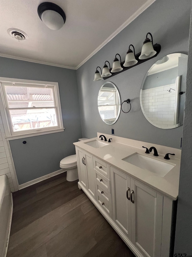 bathroom with toilet, wood finished floors, a sink, and visible vents