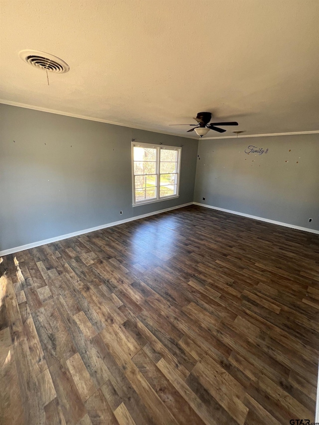 empty room featuring crown molding, dark wood-type flooring, visible vents, and baseboards