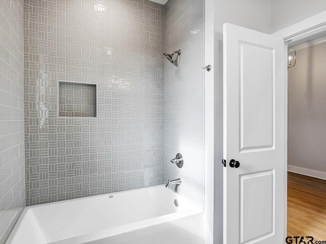 bathroom with wood-type flooring and tiled shower / bath