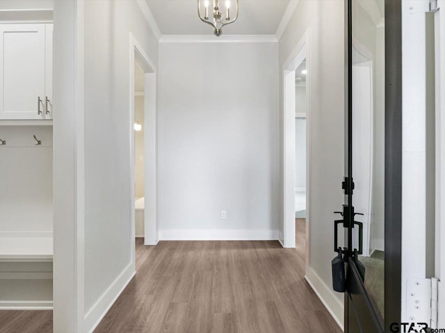 corridor featuring an inviting chandelier, ornamental molding, and light hardwood / wood-style flooring