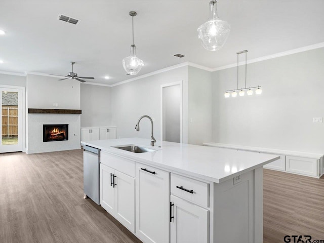 kitchen with a center island with sink, dishwasher, white cabinets, and hanging light fixtures