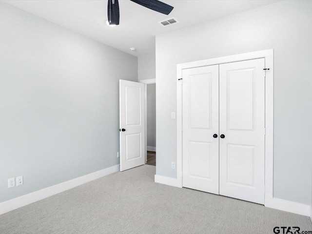 unfurnished bedroom featuring ceiling fan, a closet, and light colored carpet