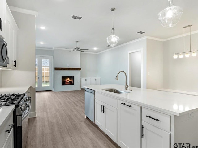 kitchen with white cabinets, hanging light fixtures, sink, and appliances with stainless steel finishes