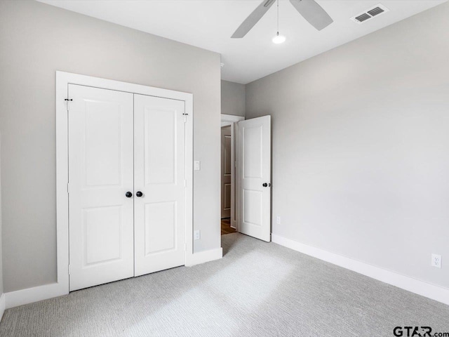 unfurnished bedroom featuring ceiling fan, light colored carpet, and a closet