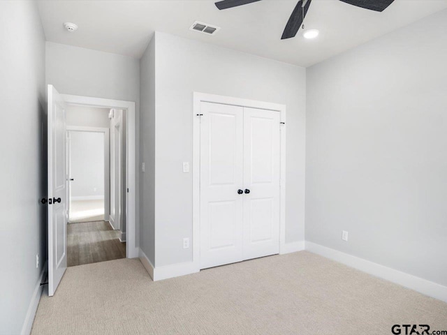 unfurnished bedroom with ceiling fan, light carpet, and a closet