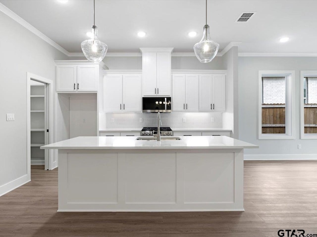 kitchen featuring white cabinetry, an island with sink, and decorative light fixtures