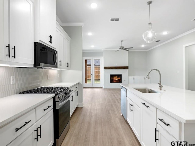 kitchen featuring decorative backsplash, stainless steel appliances, sink, white cabinets, and hanging light fixtures